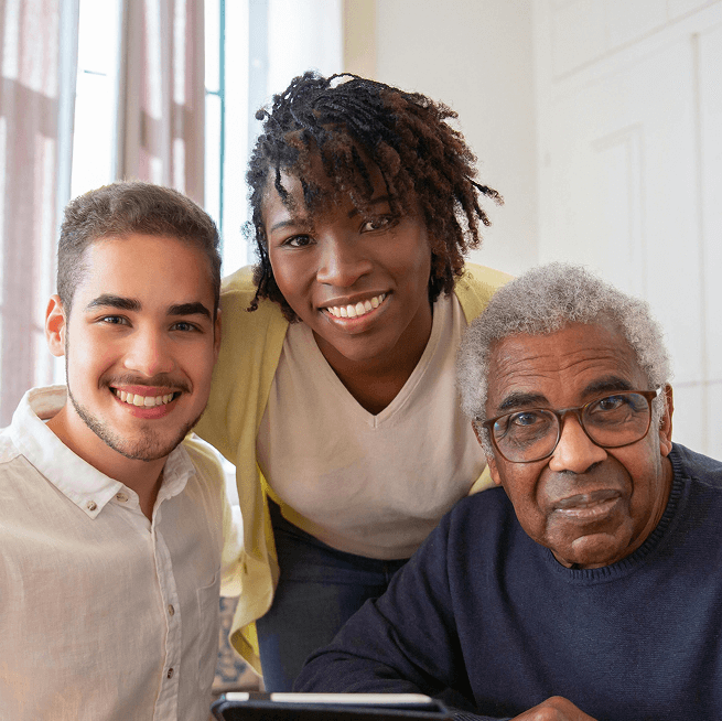 Circular group photo featuring three adults smiling broadly. One has long dark hair, another has short dark hair, and the third is older, with grey hair.